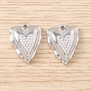 Dettaglio di un ciondolo a cuore irregolare in argento con piccole perle bianche e anello