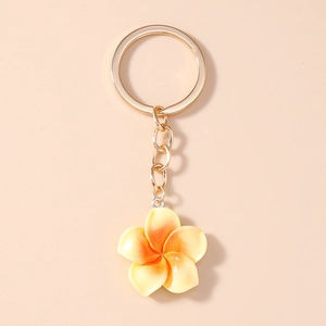 Detail of yellow gradient plumeria flower keychain with golden plated metal ring