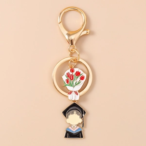 Close-up of golden graduation keychain with enamel tulip bouquet and graduate charms