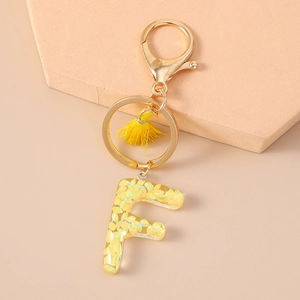 Detailed close-up of resin letter F keychain with yellow petals and gold tassel