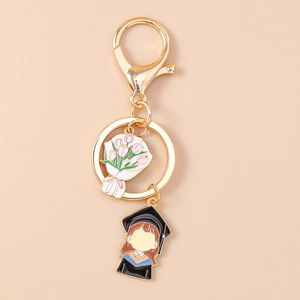 Detailed close-up of golden graduation keychain with tulip and girl enamel pendants