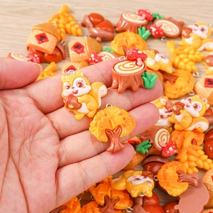 Hand holding cartoon squirrel and acorn resin charms for DIY jewelry making and crafts