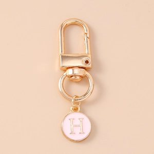 Macro view of a gold lobster clasp with a pink enamel round pendant featuring the letter H