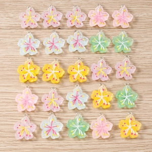 Assorted resin floral charms with silver loops for DIY jewelry on wooden background