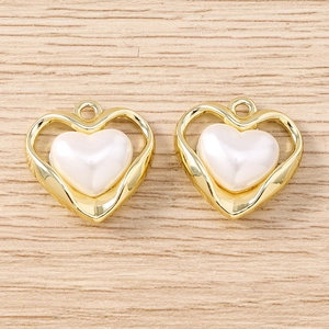 Dettaglio di ciondoli dorati a forma di cuore con intarsio in madreperla su legno chiaro