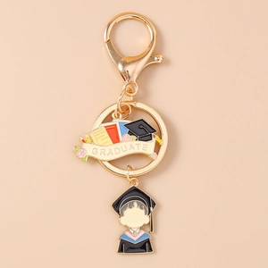 Detail of gold enamel graduate keychain featuring a mortarboard hat and cartoon graduate