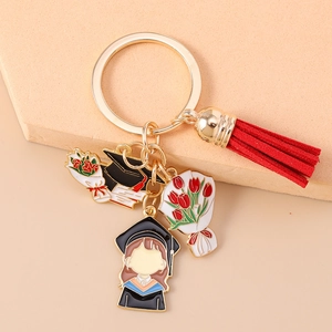 Close-up of golden graduation keychain with red tassel and enamel student charms