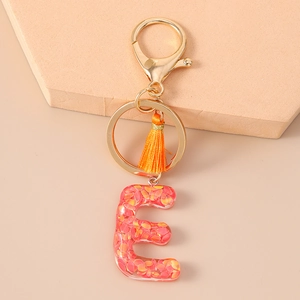 Close-up of letter E keychain with orange sequins, silk tassel, and gold lobster clasp