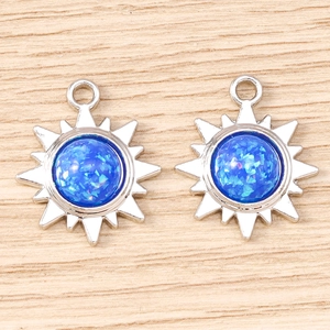 Détail de breloques soleil argentées avec paillettes bleues pour création de bijoux DIY