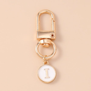 Detail of a golden letter I keychain with a white enamel round pendant and lobster clasp