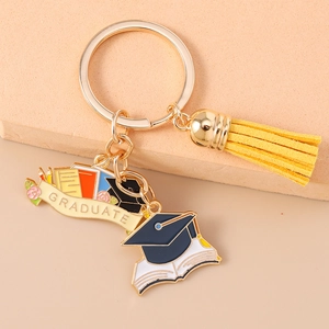 Detail of graduation keychain featuring enamel charms, graduate banner, and yellow tassel