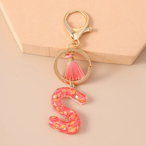 Detail of glitter resin letter S keychain with pink tassel and gold metal hardware