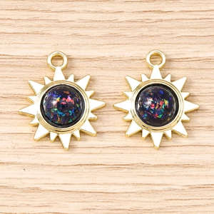 Vue détaillée de deux breloques soleil dorées avec centres opalescent irisés