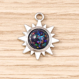 Gros plan d'un pendentif soleil argenté avec résine colorée sur fond en bois clair