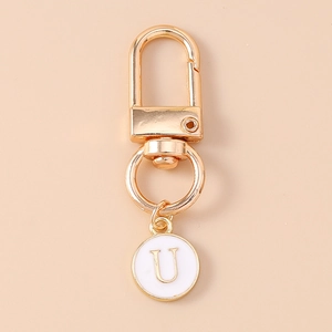 Close-up of golden letter U charm with white enamel on metal keychain with lobster clasp