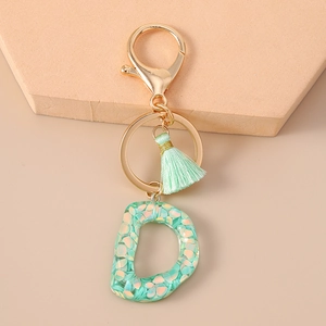 Detail of glitter-filled resin letter D keychain with mint tassel and gold hardware
