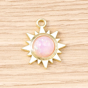 Vue macro d'un pendentif soleil doré avec opale rose irisée sur fond de bois clair