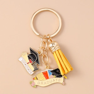 Close-up of golden graduation keychain with black cap, scroll and yellow suede tassel