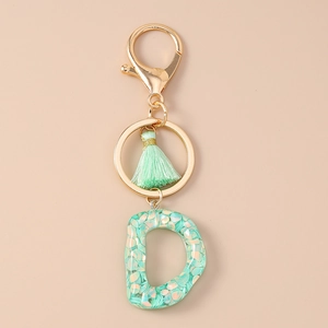 Detail of letter D resin keychain with mint green sequins, gold clasp and matching tassel