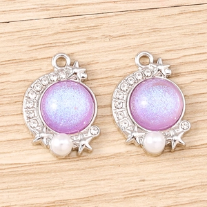 Detailed view of crescent moon pendants with purple glitter, pearls and tiny stars