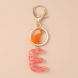 Detail of letter E resin keychain with pink orange sequins and orange silk tassel
