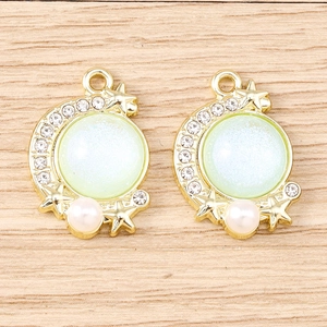 Macro view of gold moon charms with mint opal stones and pearl accents for DIY jewelry