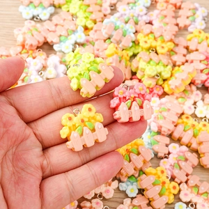 Detail view of colorful resin flower charms for DIY jewelry making held in palm