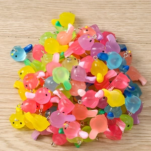 Macro shot of colorful resin bird charms for DIY jewelry making with metal rings