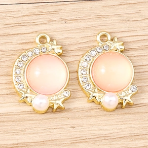Detail of moon-shaped gold pendants with pink opal gemstones and pearl drops