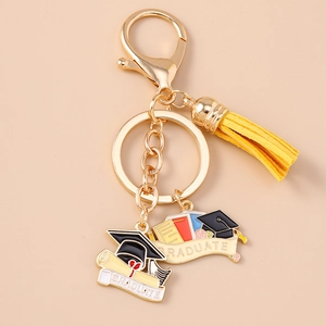 Detail of golden graduate keychain with yellow tassel, enamel books and cap pendant