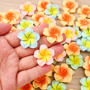 Close-up of resin frangipani charms with colorful gradient petals for DIY jewelry making