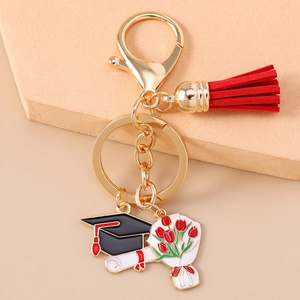 Detail of graduation keychain with doctoral hat, diploma scroll and red tassel charms