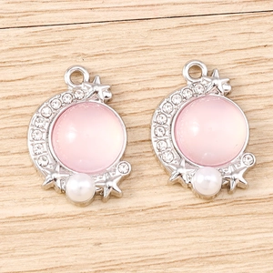 Detailed view of silver moon charms with pink stone and small sparkling rhinestones