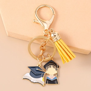 Close-up of golden graduation keychain with yellow tassel and enamel cartoon pendants