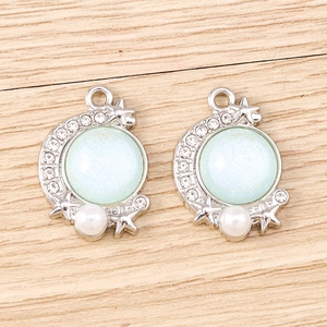 Detailed macro view of mint green moon and star charms with rhinestones and faux pearls