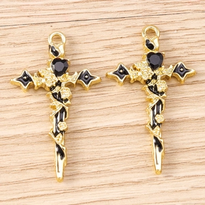 Gothic gold cross pendant with black enamel heart and rose vine detail on wood background