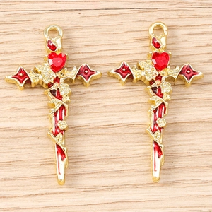 Detailed view of gold cross pendants with red heart stones and rose vine accents