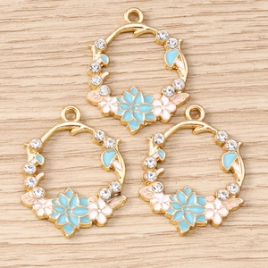 Pendentifs couronne de fleurs avec émail et cristaux sur un fond en bois clair