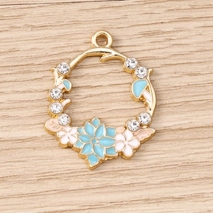 Détail des breloques couronne de fleurs dorées avec émail et accents de cristaux
