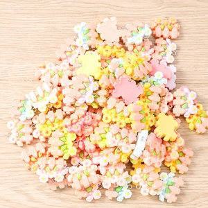 Macro detail of mixed floral resin pendants in pastel colors on wooden background