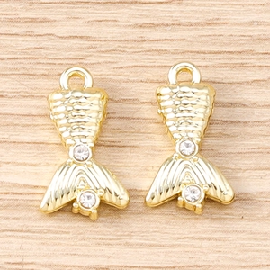Détail macro d'une paire de breloques queue de sirène dorées avec strass et écailles fines