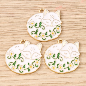 Detailed macro view of three white enamel fox pendants with golden trim and floral details