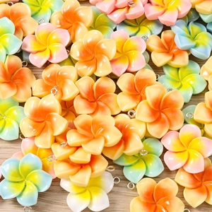 Detailed view of colorful resin plumeria flower charms with silver jump rings for DIY jewelry