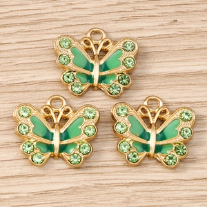 Detailansicht der goldenen Schmetterlingsanhänger mit grünem Emaille und Strasssteinen