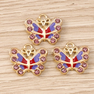 Detailaufnahme goldener Schmetterlingsanhänger mit lila Emaille und rosa Strasssteinen