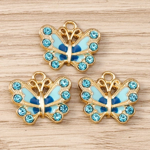 Nahaufnahme von drei blauen Schmetterlingsanhängern mit Strass auf Holzgrund