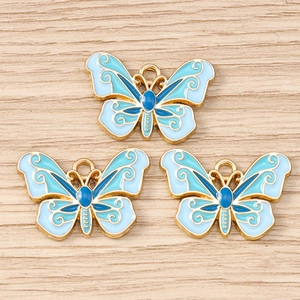 Detailed macro view of three blue enamel butterfly charms with gold metal filigree for DIY jewelry
