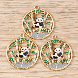 Vue détaillée des pendentifs panda et bambou en émail sur un fond en bois clair