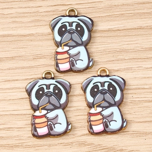 Vue détaillée de trois breloques carlin en émail pour bijoux DIY sur fond bois clair