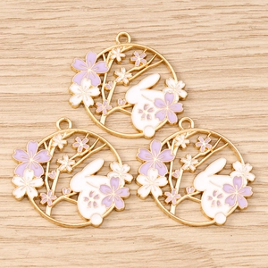 Detail showing three enamel rabbit and sakura pendants with golden metal edges for jewelry DIY